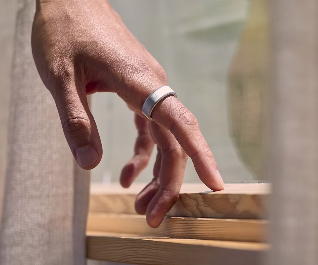A person wearing a Brushed Silver Oura Ring 4 touching a windowsill